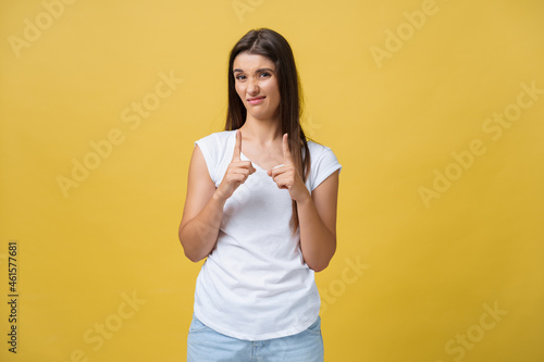 Portrait disappointed awkward attractive woman in white shirt, raising hand and shaping small item, looking at fingers and frowning from dislike and regret, standing over yellow background photo