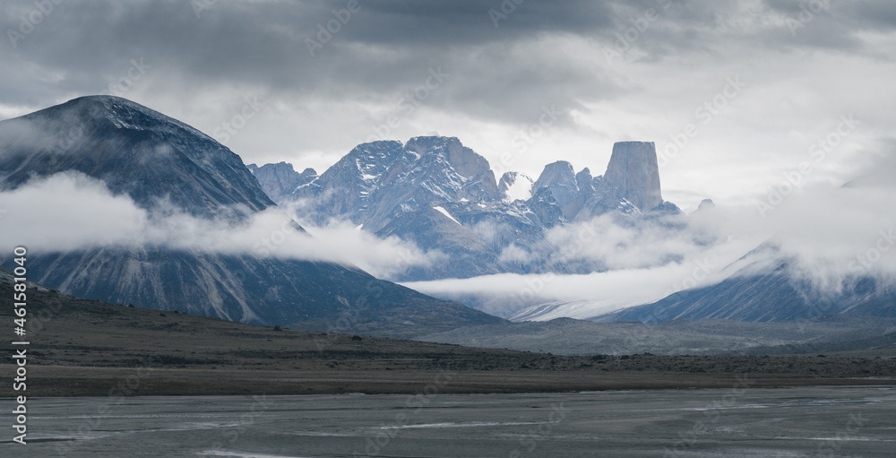 Iconic granite rock of Mt.Asgard towers above Turner glacier on a very cloudy and foggy day in remote arctic valley of Akshayuk pass, Baffin Island, Canada. Landscape in remote wilderness far north.