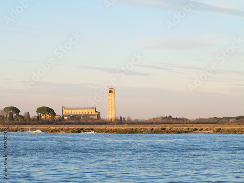 A colourful, rainbow sunset over a small island with a lighthouse near Venice, Italy.