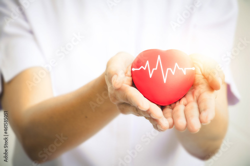 A hand holding red heart.She is Left  right hand holding it.heart health  happy volunteer charity The photo shows the principle of caring and good health.