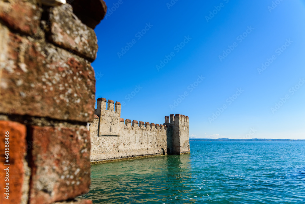 Facade of the castle of Sirmione surrounded by water.