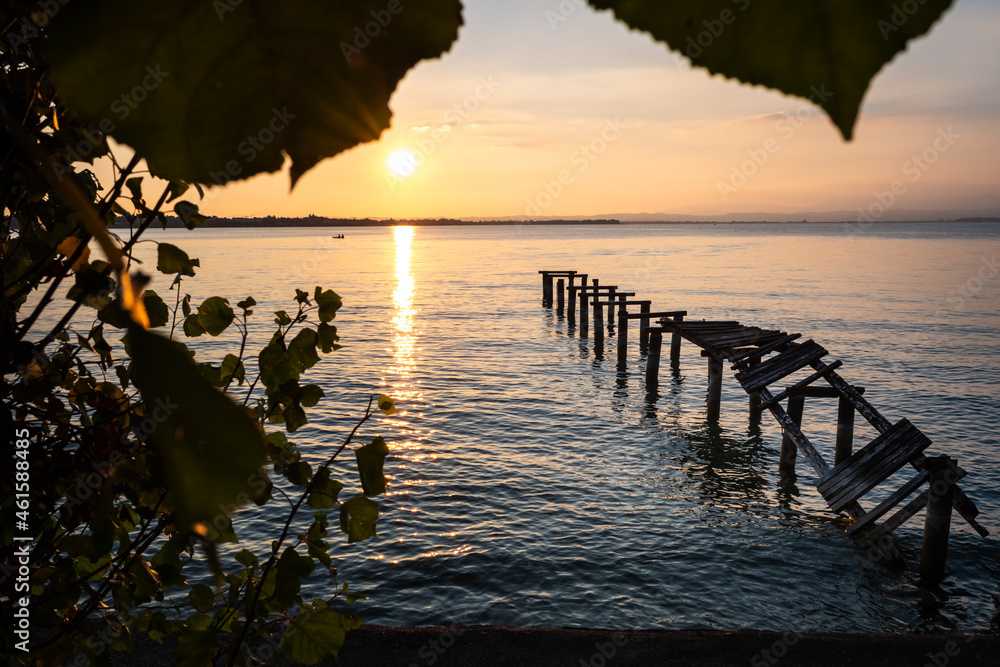 Obraz premium An old ramshackle pier with broken boards, during a beautiful sunset on a quiet lake.