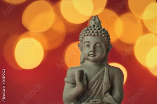 Buddha statue on red background with golden bokeh .Meditation and relaxation symbol.Buddhism religion 
