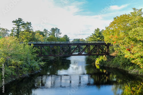 Eastern Maine Railroad crossing bridge over river on an early fall evening