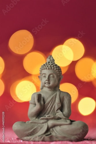 Buddha statue on red background with golden bokeh .Meditation and relaxation symbol.
