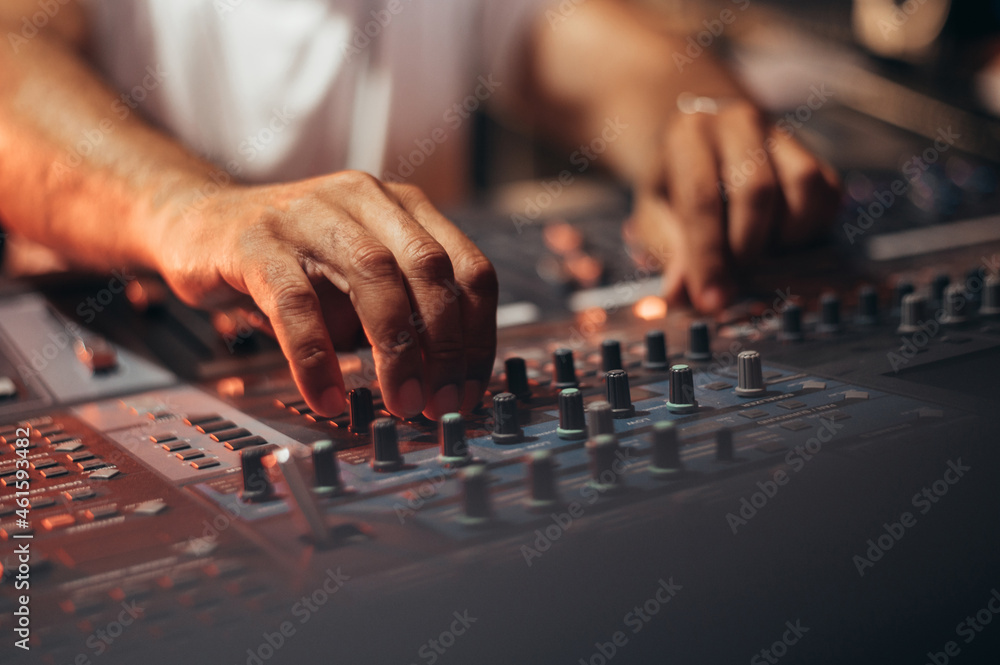 Music producer hands while working on a mixing soundboard while in his studio Music producer hands while working on a mixing soundboard while in his studio