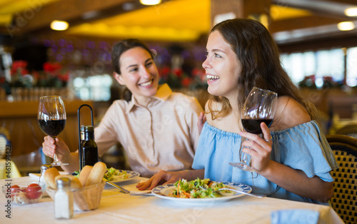 Two girls are discussing something fun at a table in a restaurant