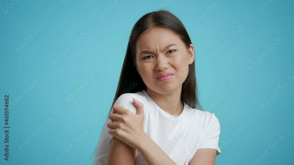 Asian Lady Massaging Shoulder Suffering From Joints Pain, Blue Background Asian Lady Massaging Shoulder Suffering From Joints Pain, Blue Background