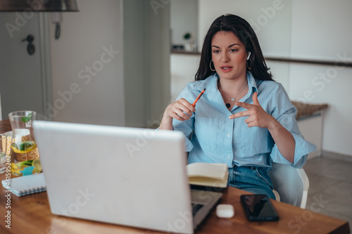 Beautiful young businesswoman using a laptop while working at home