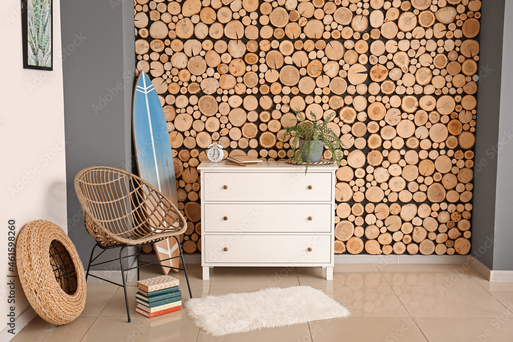 Obraz premium Interior of modern stylish room with surfboard, wicker armchair and chest of drawers