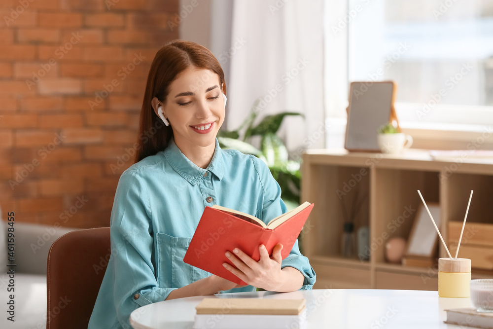 Young woman with earphones and book at home Young woman with earphones and book at home