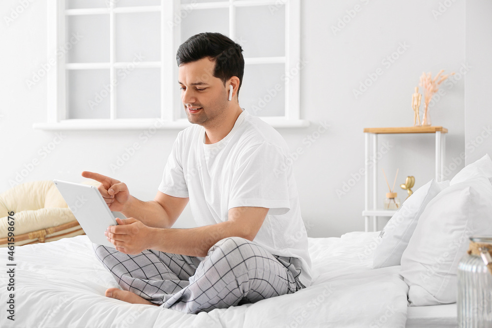 Young man with tablet computer and earphones in bedroom Young man with tablet computer and earphones in bedroom