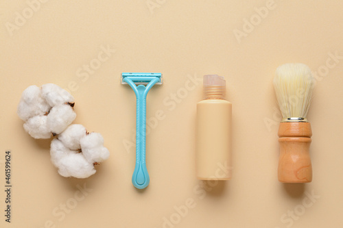 Safety razor  shaving brush  bottle of cosmetic product and cotton flowers on color background