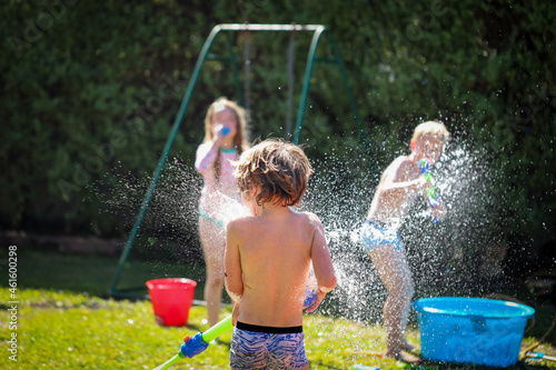 Kids enjoying backyard water fight in summer photo