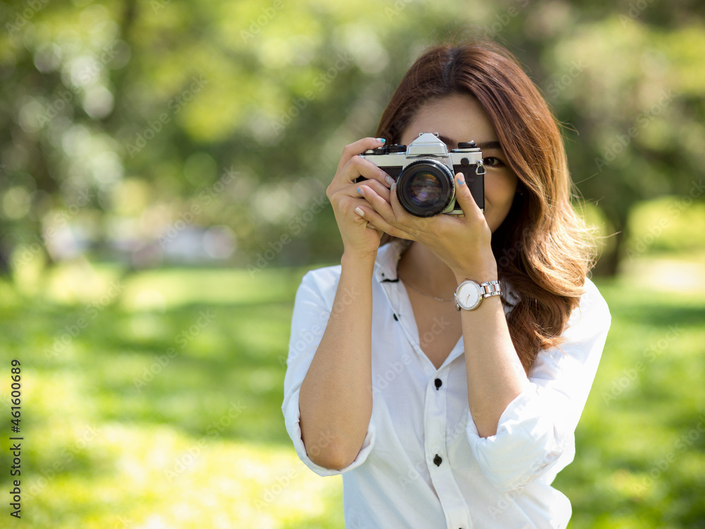 Female photographer taking photo with vintage or retro camera in a park