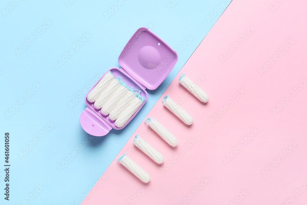 Tampons storage box and tampons on pink and blue background, top view Tampons storage box and tampons on pink and blue background, top view