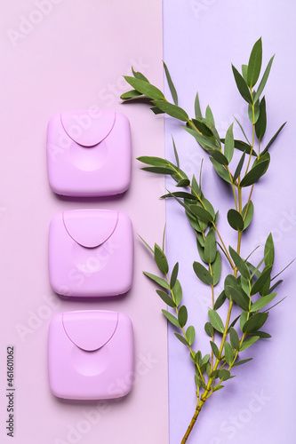 Tampons storage boxes in row and green branch on lilac background