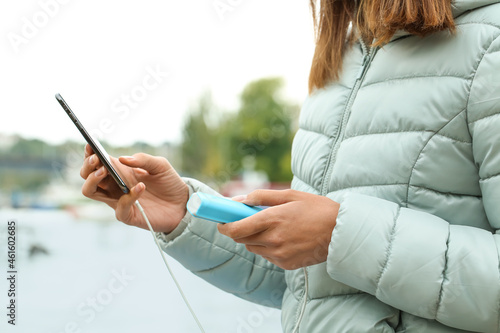 Young woman with phone and power bank near river