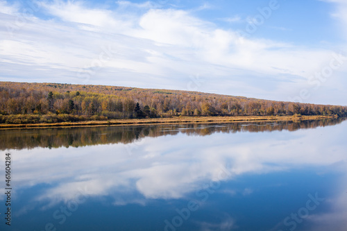 Beautiful  wide river autumn among the woods. Calm and quiet place with autumn colors. In the middle of the river island. View from the top to the distance