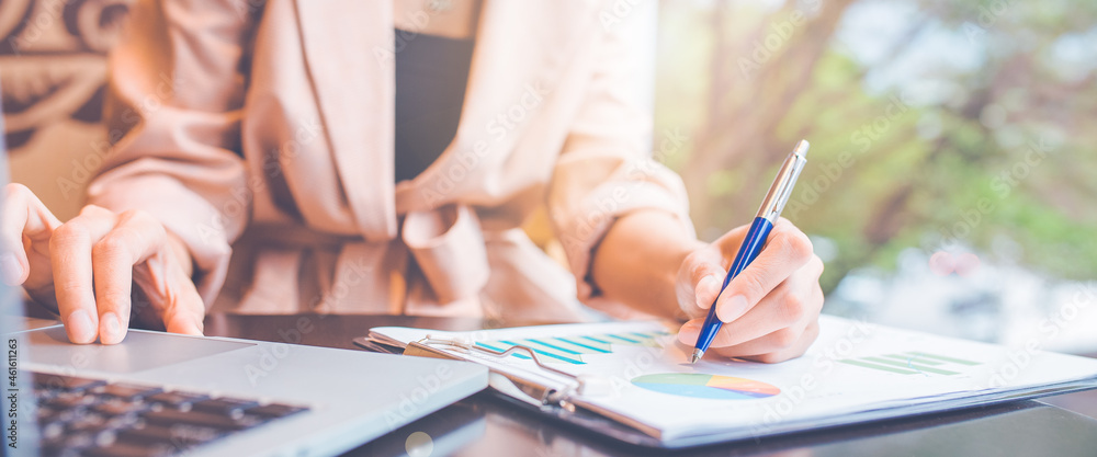 businessman analyzing the stock situation.She uses a pen and a laptop computer.