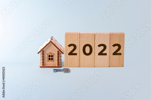 Wooden house model, blocks with Inscription numbers 2022 and key. Concept of buying and selling homes and real estate in new year. Home Insurance, property and mortgage,