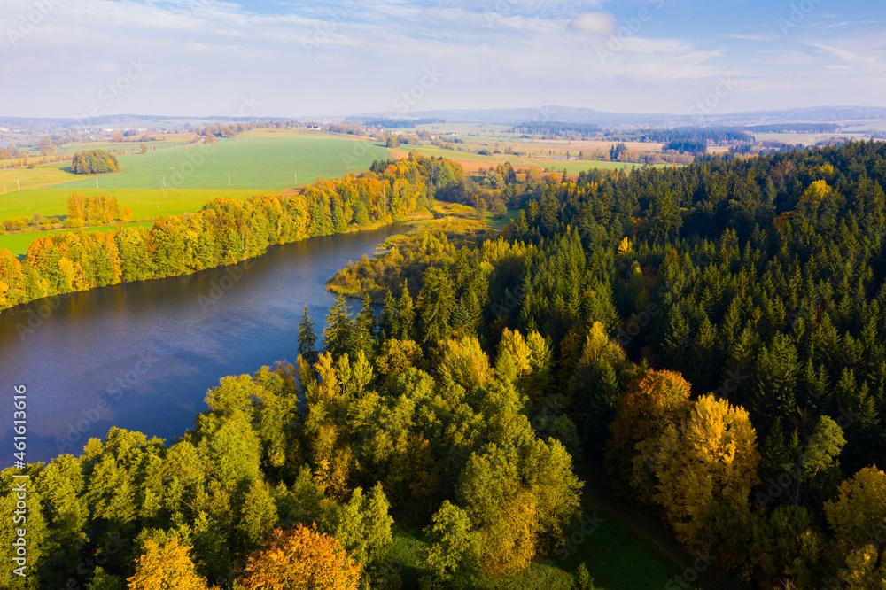 View from drone of forest landscape around picturesque lake on sunny autumn day