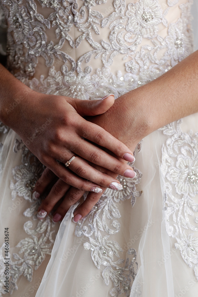 Hands of the Hands of the bride close-up on the background of the wedding dress. Vertical orientation Hands of the Hands of the bride close-up on the background of the wedding dress. Vertical orientation