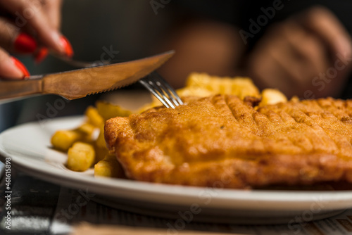 Close up view of someone eating fried food and french fries on a plate