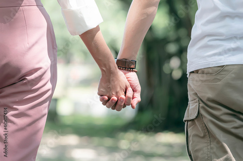 Cropped shot of young man and woman holding hands together while standing outdoors.