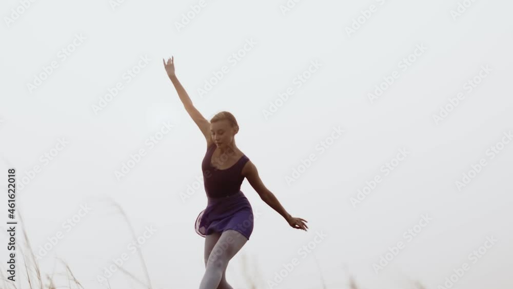 White caucasian woman dances a smooth dance against background of sky and sun. Classical ballet against the sunset, an art concept White caucasian woman dances a smooth dance against background of sky and sun. Classical ballet against the sunset, an art concept