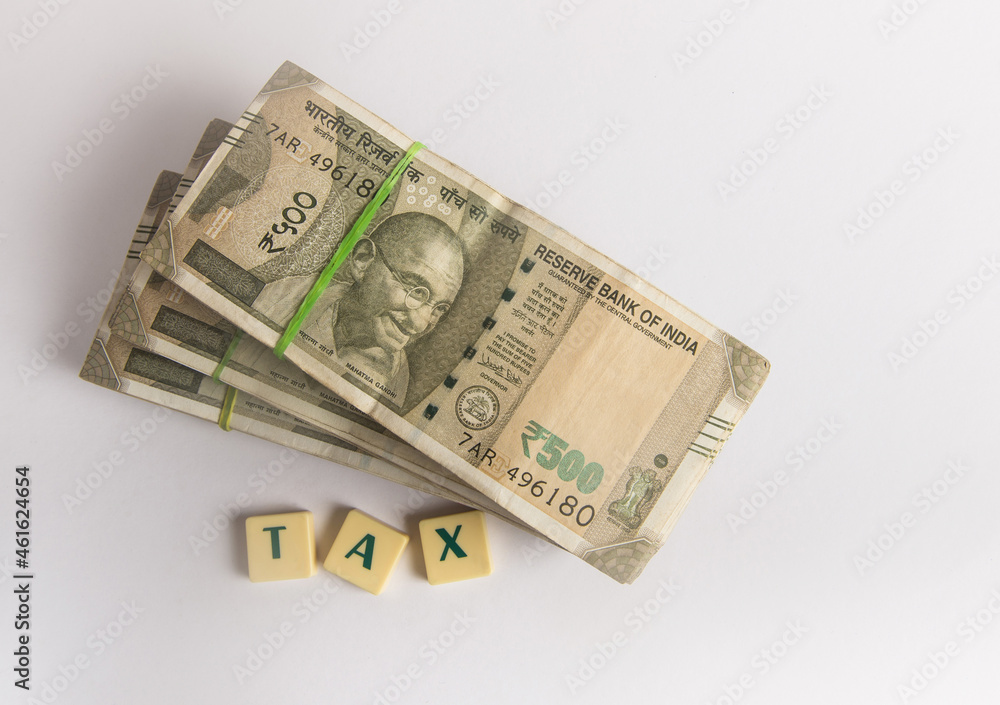 Stack of five hundred Indian rupee currency notes places on white background with title 'TAX'. Photo for Indian economy and taxes. Stack of five hundred Indian rupee currency notes places on white background with title 'TAX'. Photo for Indian economy and taxes.