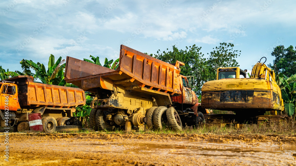 Obraz premium Wreck of heavy machinery in the junkyard of forestry company. Broken old rusty truck and excavator