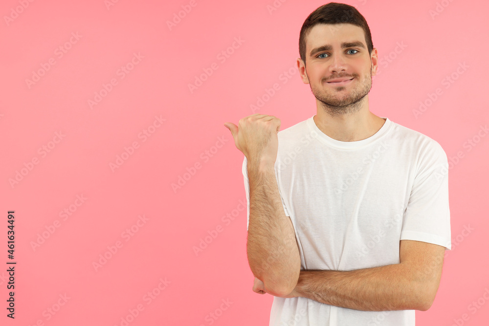 Young man pointing on space for text on pink background Young man pointing on space for text on pink background