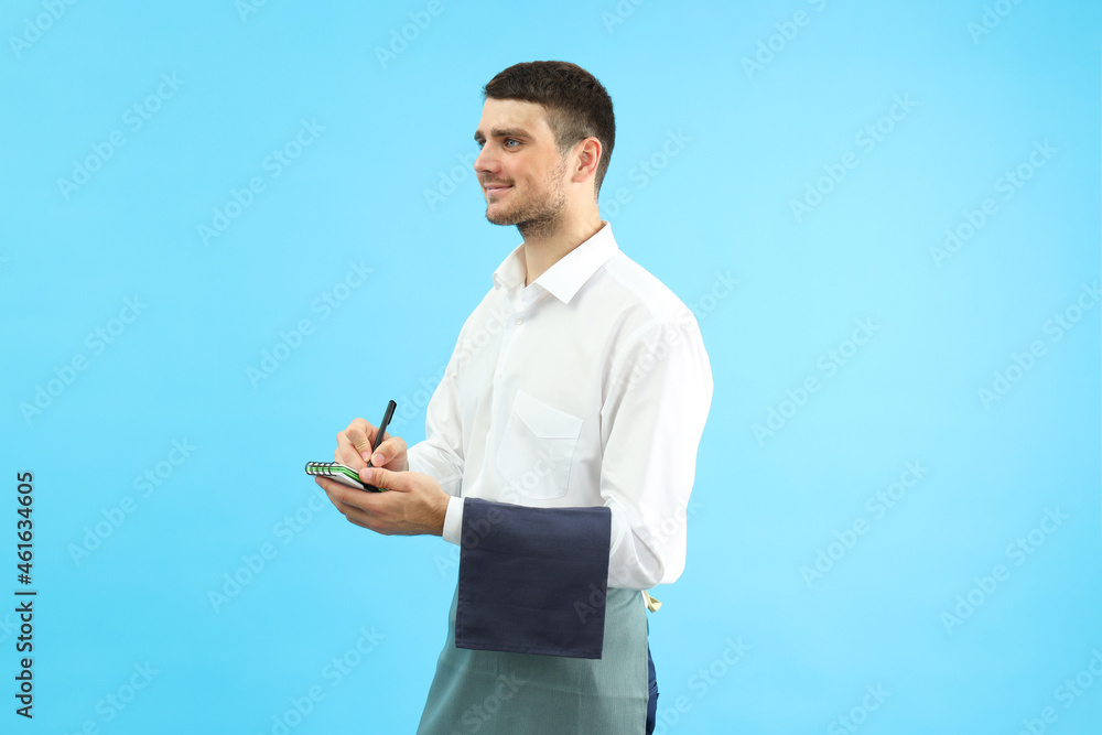 Smiling waiter with notebook on blue background Smiling waiter with notebook on blue background