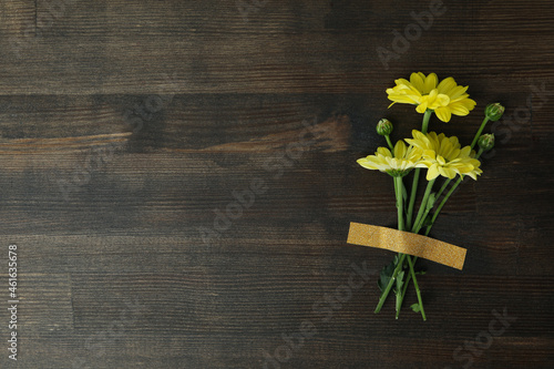 Yellow chrysanthemums stuck on wooden background, space for text