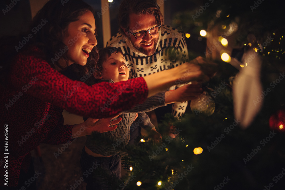 Family decorating Christmas tree at home - obrazy, fototapety, plakaty 
