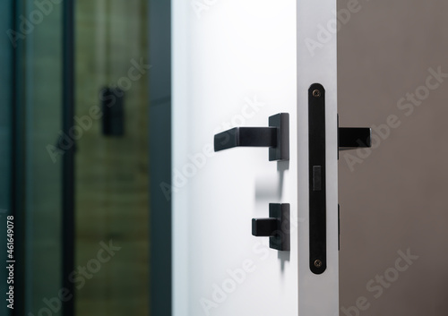 Foto Black metal latch and handles on a white wooden bathroom door