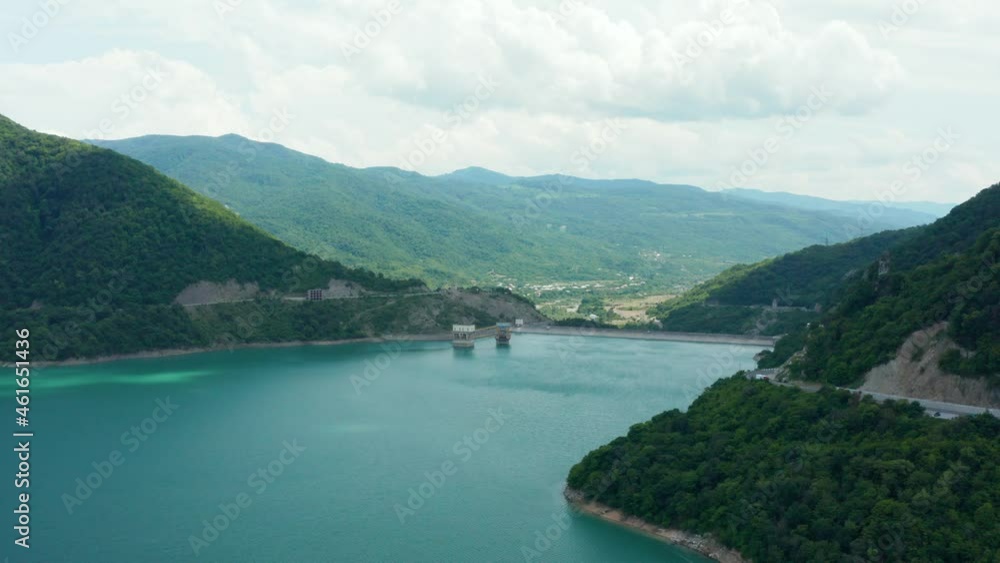 Aerial panoramic view of mountain valley turquoise lake surrounded by green lush forest and mountain road. Overcast sky. Forward camera movement. 4k footage. Aerial panoramic view of mountain valley turquoise lake surrounded by green lush forest and mountain road. Overcast sky. Forward camera movement. 4k footage.
