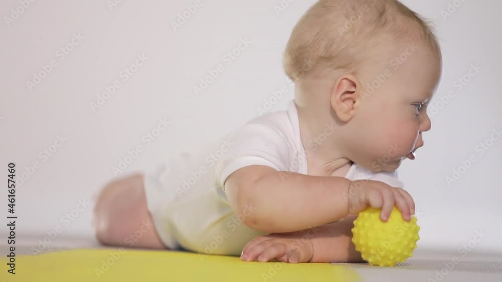 Cute baby in white clothes learns to crawl on the floor with toys. Domestic life Cute baby in white clothes learns to crawl on the floor with toys. Domestic life