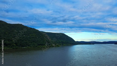 Aerial drone footage rising over the Hudson River in New York's Hudson Valley with Storm King Mountain in the background at susnet. Storm King mountain is part of the larger appalachian mountain range