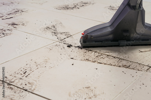 the brush of the washing vacuum cleaner removes the traces of the sole of the shoes on the floor of the ceramic tile, close-up photo
