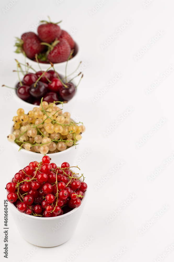 Blurred image of various fruits and berries in white plates on a white background with space for entering text. Blurred image of various fruits and berries in white plates on a white background with space for entering text.