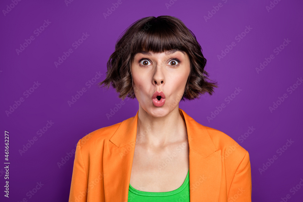 Photo of shocked pretty young lady wear orange jacket big eyes isolated violet color background Photo of shocked pretty young lady wear orange jacket big eyes isolated violet color background