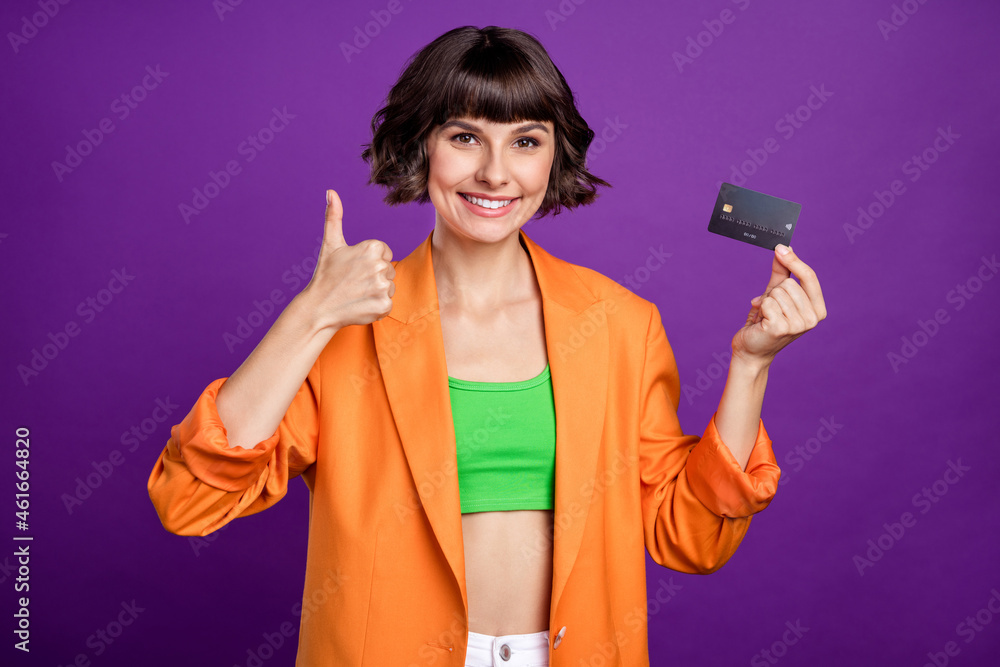 Photo of optimistic young brunette lady hold card thumb up wear orange blazer top isolated on violet color background Photo of optimistic young brunette lady hold card thumb up wear orange blazer top isolated on violet color background
