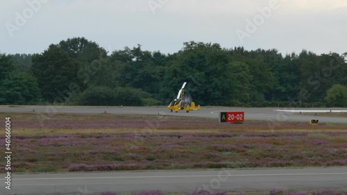 A Gyrocopter Taxiing onto the Runway of an Airfield on a Cloudy Day. photo