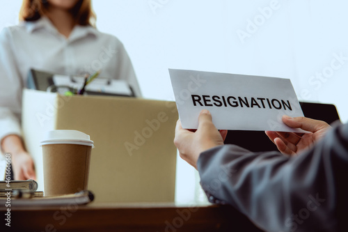 Boss receives a letter of resignation from a female employee. She collect her office accessory to a box and prepares to go home.
