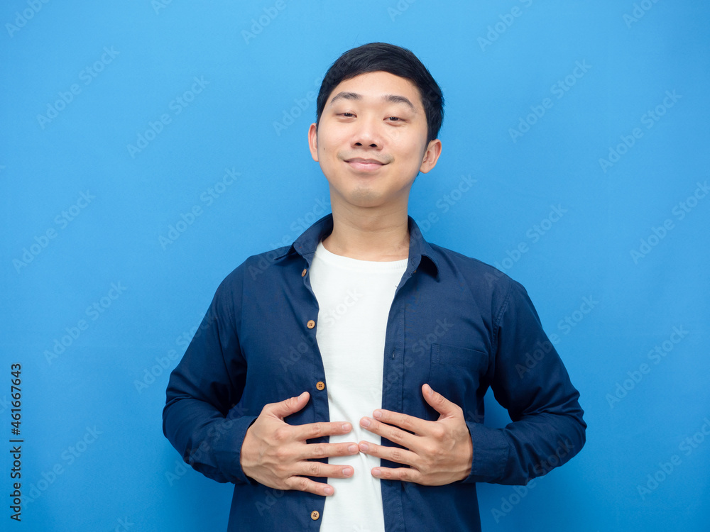 Asian man touch his belly feeling full from food blue background Asian man touch his belly feeling full from food blue background