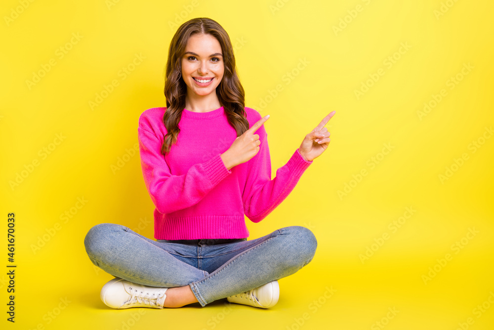 Full size photo of young happy smiling cheerful girl sit floor pointing fingers copyspace isolated on yellow color background Full size photo of young happy smiling cheerful girl sit floor pointing fingers copyspace isolated on yellow color background