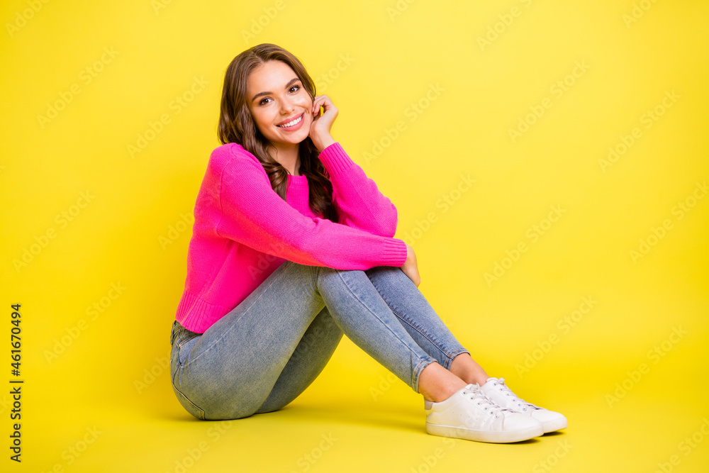 Full length profile side photo of young attractive girl happy positive smile sit floor isolated over yellow color background Full length profile side photo of young attractive girl happy positive smile sit floor isolated over yellow color background
