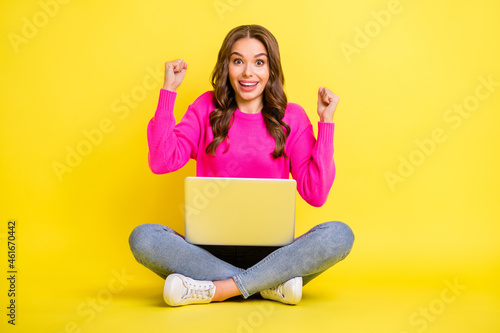 Full size photo of young happy crazy excited good mood girl work laptop raise fists in victory isolated on yellow color background